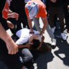 two people fighting on the ground in the middle of a crowd of protesters