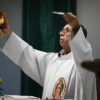 Catholic priest at mass holds up the chalice and the bread