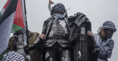pro-Hamas protesters wrap Palestinian flag and Keffiye around the statue