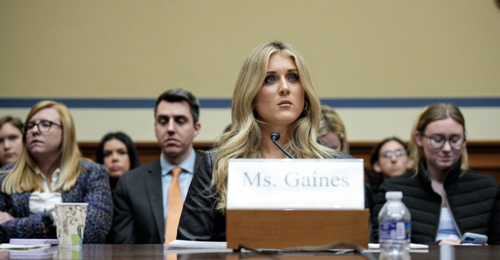 Riley Gaines sitting at a witness table testifying during a House committee hearing