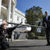 Joe Biden talks to reporters extending microphones to him in front of the White House.