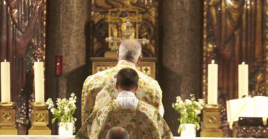 Priests in ornate vestments face the crucifix in a Latin Mass.
