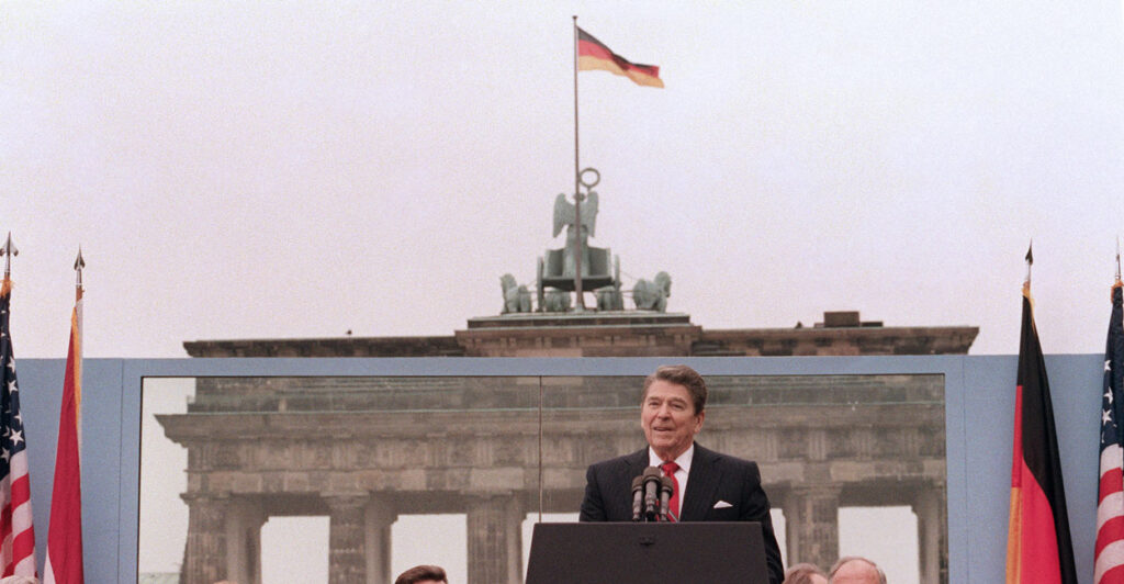 Former President Ronald Reagan giving a speech on a podium.