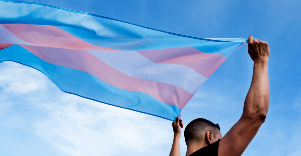 A young person waving a transgender flag.