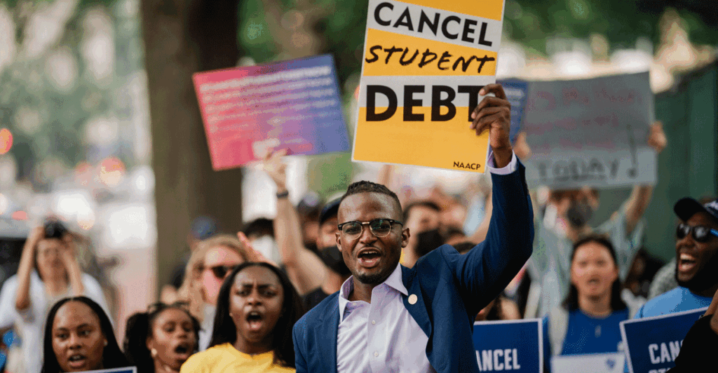 Several black students outdoors holding up signs saying cancel student debt