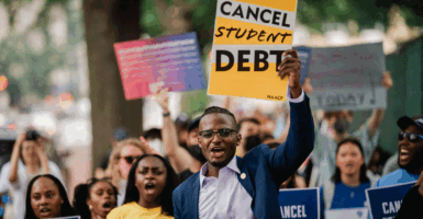Several black students outdoors holding up signs saying cancel student debt
