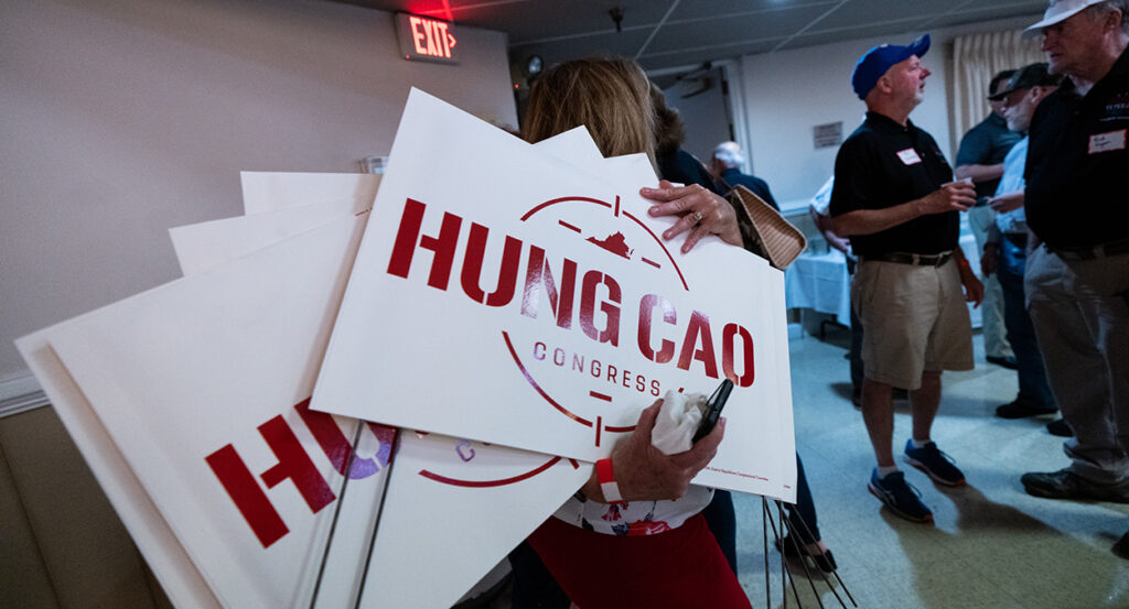 A woman holds campaign signs for Hung Cao.
