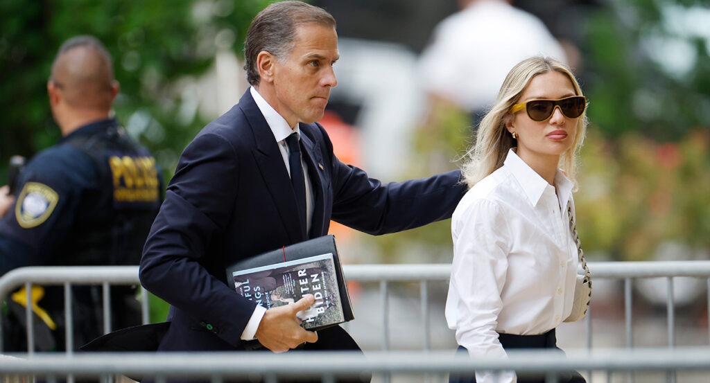 Hunter Biden in a suit stands behind his wife, Melissa Cohen, in a white dress shirt