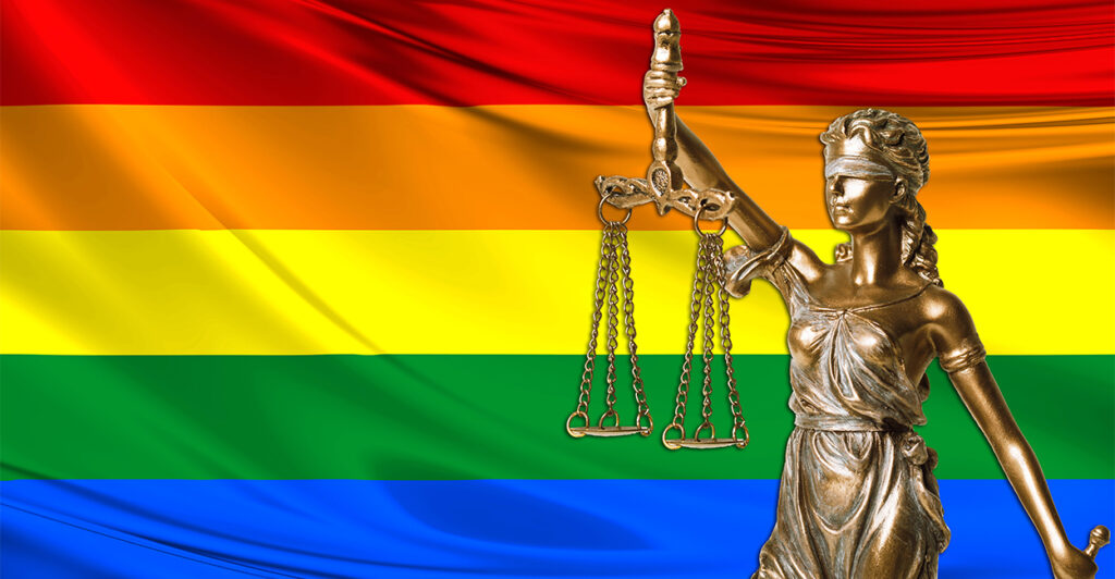 Statue of Lady Justice with an LGBTQ flag in the background