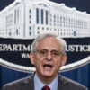 Merrick Garland speaks at a podium in front of the Department of Justice emblem.