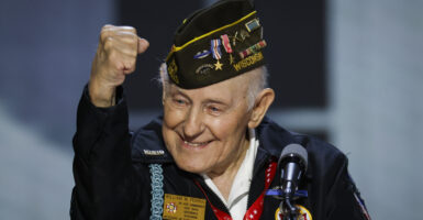 WWII Veteran Sergeant William Pekrul pumps his fist and smiles while standing at the podium on stage.
