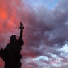 A silhouette of the Statue of Liberty with a sunset background.