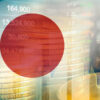 The Japanese flag with a backdrop of financial charts.