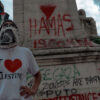 A protester wearing an "I love Palestine" T-shirt and standing in front of a monument.