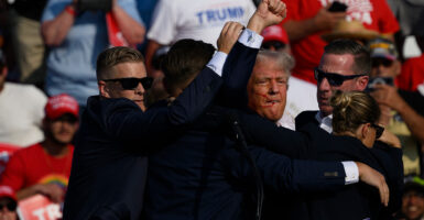 Trump holds in fist in the air surrounded by Secret Service.