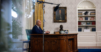 Biden sits at his desk in the Oval Office.