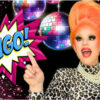 A drag queen points to the word, "Bingo!"