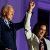 Joe Biden and Kamala Harris raising their hands and smiling.