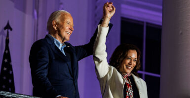 Joe Biden and Kamala Harris raising their hands and smiling.