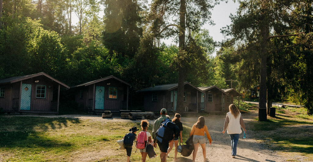 Kids walk toward a cabin in the woods.