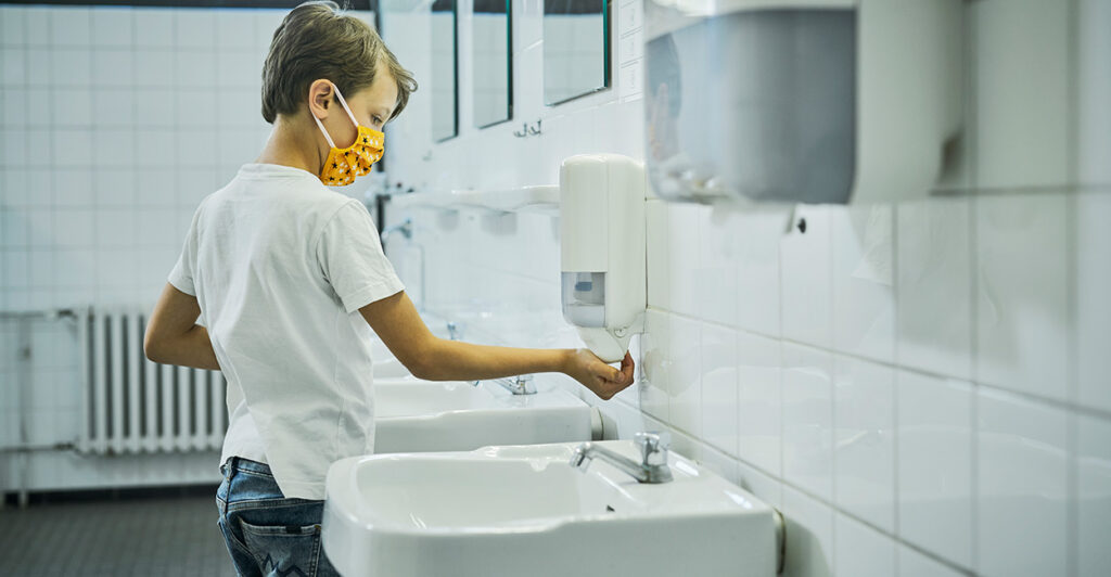 A little boy washes his hands.