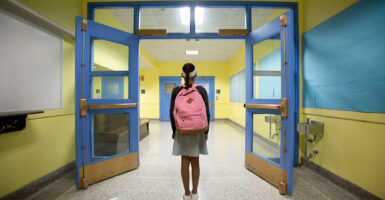 Girl walks down hallway with backpack