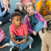 Kids sit in front of a teacher.
