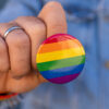 A man holds a rainbow pin.