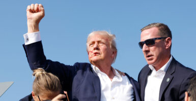 After being shot at by an assassin and with blood streaming down his face and his fist raised in the air, Donald Trump is rushed offstage by Secret Service during an outdoor rally