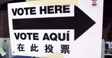 A paper sign that says "vote here" in English and Spanish