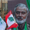 A mural of Ismail Haniyeh with flags flying around it.