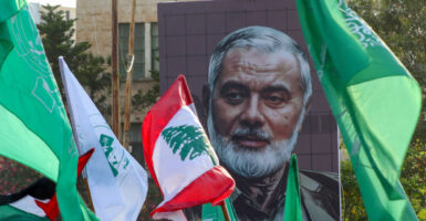 A mural of Ismail Haniyeh with flags flying around it.
