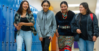 High school girls walk down hallway.