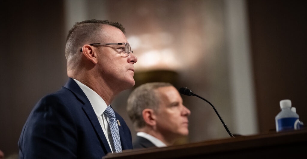 A side profile of Ronald Rowe sitting before a microphone during a hearing.