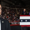 A Secret Service Agent watches the crowd as Trump speaks at the podium behind him.