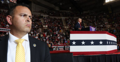 A Secret Service Agent watches the crowd as Trump speaks at the podium behind him.