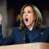 Kamala Harris with finger raised in a blue suit.