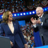 Kamala Harris and Tim Walz laughing in suits