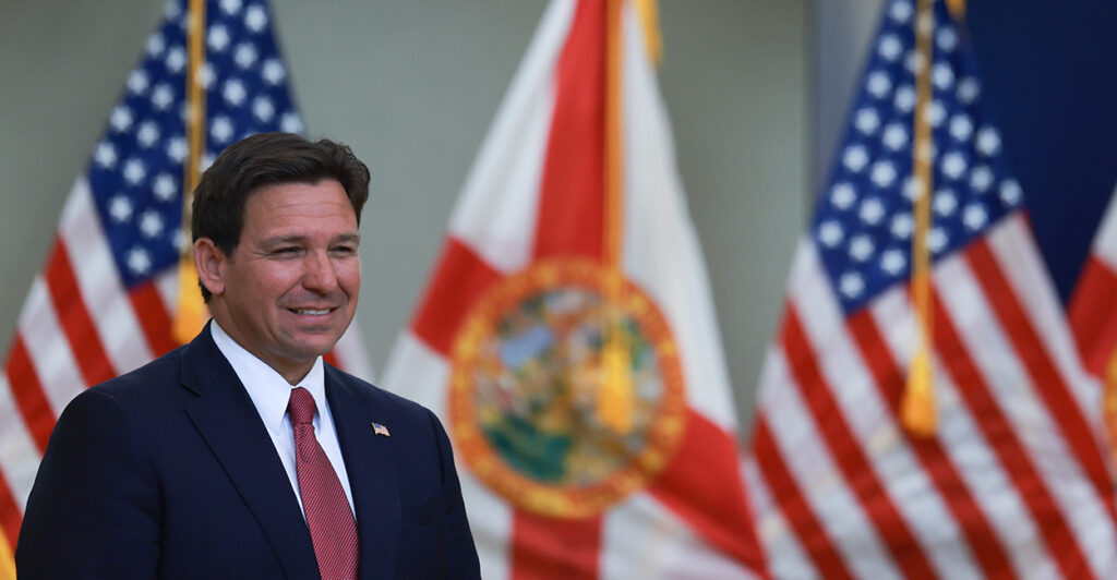 DeSantis smiles in front of flags.