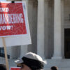 Protester holding a sign that says End Gerrymandering Now