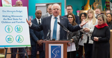 Walz talks with his hands behind a podium.