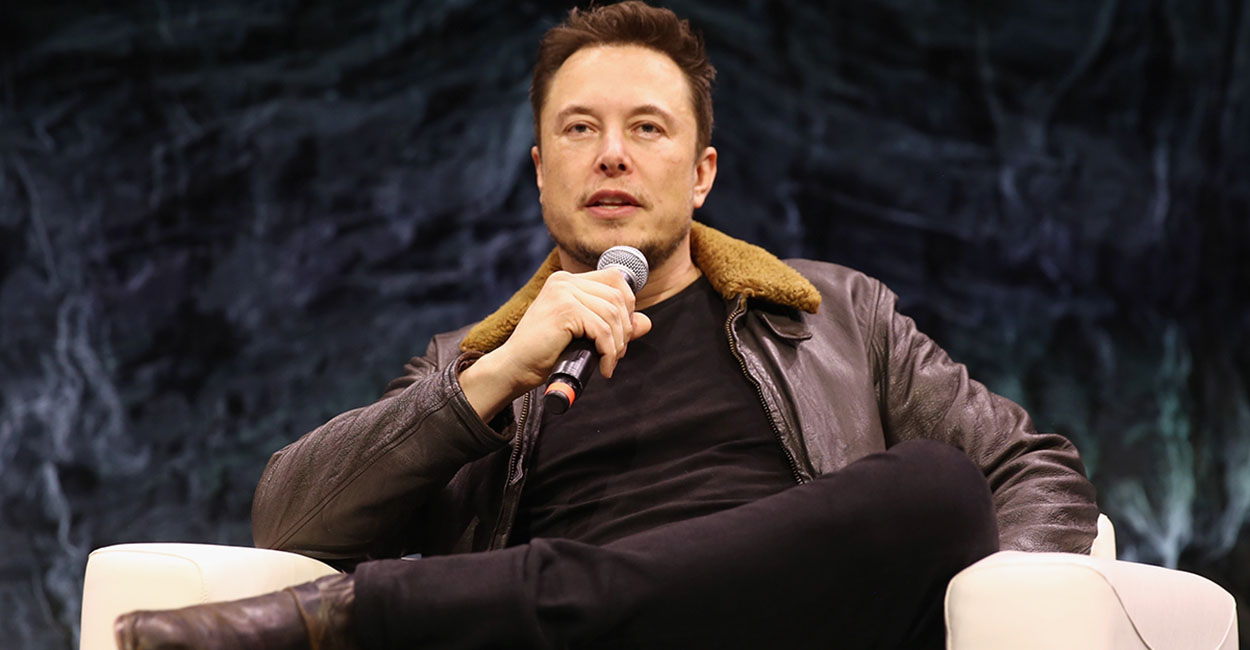 Elon Musk sitting in a suit