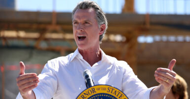 Gavin Newsom in a white shirt behind a governor's seal