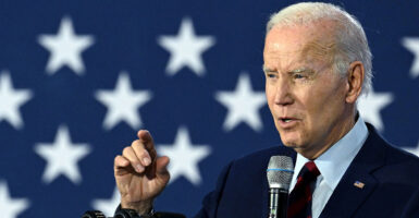 President Joe Biden in a black suit in front of an American flag