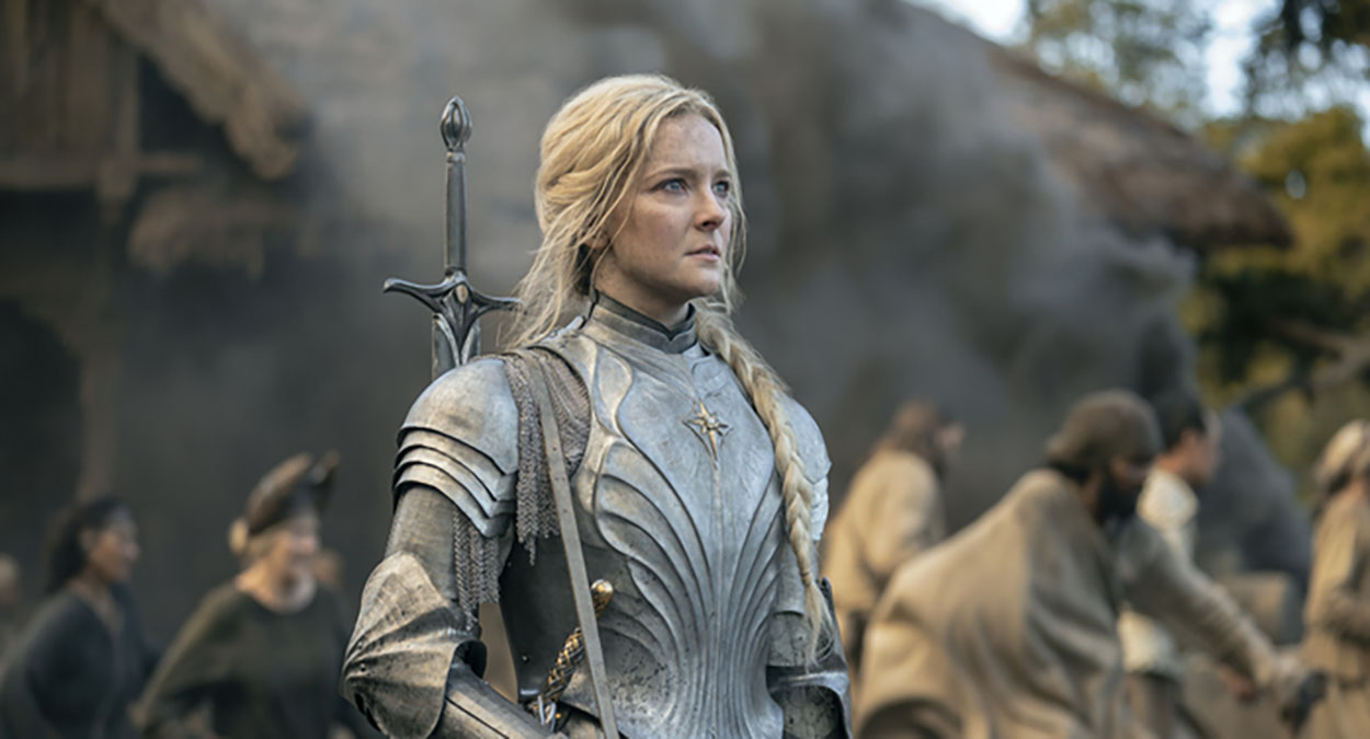 Blonde woman Morfydd Clark in armor with a sword