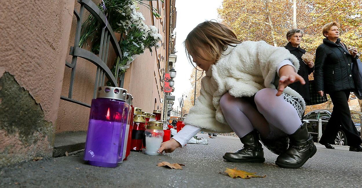 A young girl places a candle outside the French Embassy in Zagreb, Croatia, November 14. (Photo: Antonio Bat/Newscom)